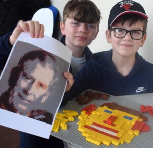 kids holding LEGO portrait of King Charles