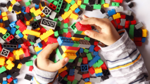 image shows a close up of a child's hands playing with plastic toy building blocks